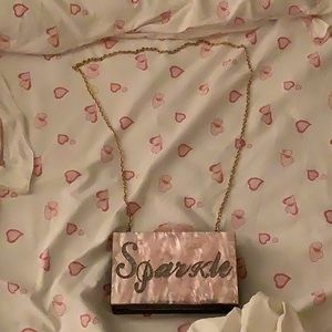 A pink glittery purse with gold chain.